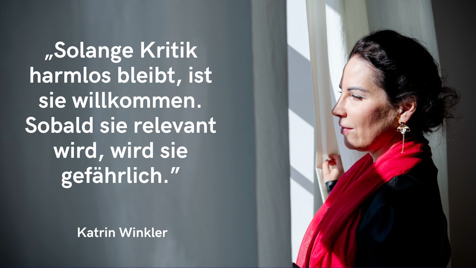 Auf der rechten Seite des Bildes ist eine Frau im Profil zu sehen, die nach draußen blickt. Sie hat dunkle Haare, die zu einem Dutt gebunden sind, und trägt auffällige Ohrringe sowie einen roten Schal über einem dunklen Oberteil. Sie steht an einem Fenster und hält leicht den Vorhang, durch den Tageslicht ins Bild fällt. Ihr Gesicht wirkt ruhig und nachdenklich. Auf der linken Seite des Bildes befindet sich ein grauer Hintergrund mit weißer Schrift. Dort steht das Zitat: „Solange Kritik harmlos bleibt, ist sie willkommen. Sobald sie relevant wird, wird sie gefährlich.“ Unter dem Zitat steht der Name: Katrin Winkler