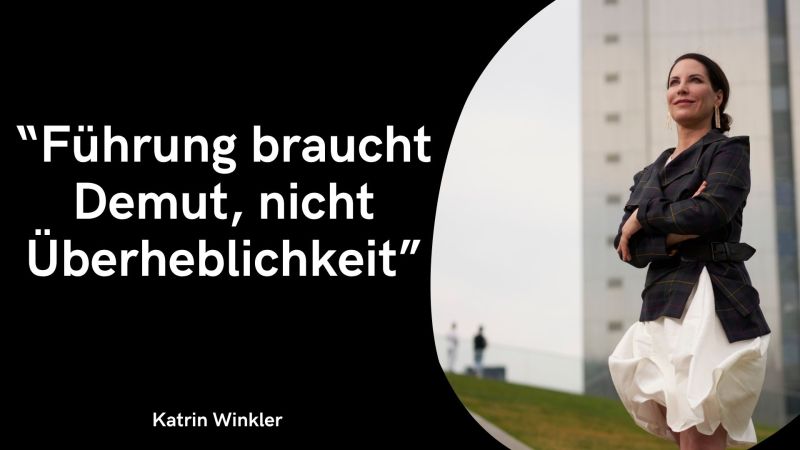 Das Bild passt zum gewohnten Zitat-Layout: Linker Bereich: Auf schwarzem Hintergrund steht in großen weißen Buchstaben das Zitat: „Führung braucht Demut, nicht Überheblichkeit“ Ganz unten links steht in weißer Schrift der Name Katrin Winkler. Rechter Bereich: In einer geschwungenen Form schließt ein Foto an. Es zeigt Katrin Winkler draußen vor einem modernen Gebäude mit verschränkten Armen. Sie trägt ein kariertes Sakko, einen weißen Rock und blickt leicht nach oben.